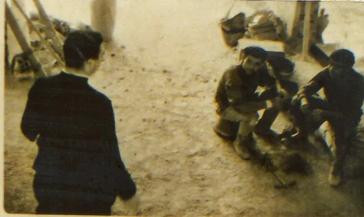 Imagen borrosa en sepia de una persona de espaldas y dos hombres sentados junto a cubos y una escalera.