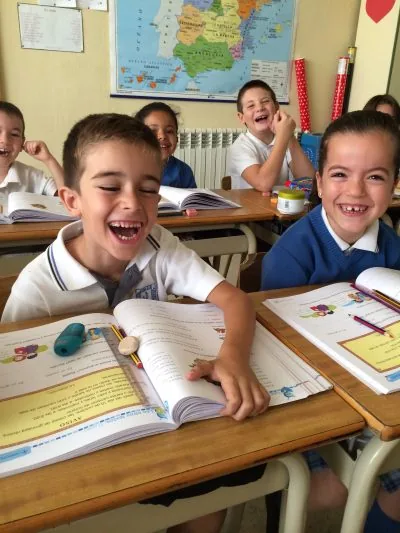 Niños sonriendo en el aula con sus cuadernos abiertos